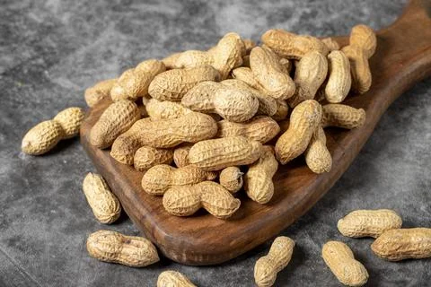 Peanuts in shell on dark background. Peanuts on a wooden serving board. close Stock Photos