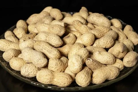 Peanuts in shell on glass plate close-up. Black background. Foto stock