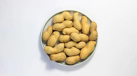 Peanuts in a shell in a saucer on a white background. The legume family. Stock Photos