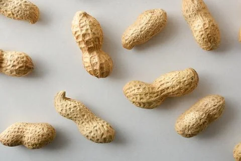 Peanuts in shell showing their shape on a white table. Stock Photos