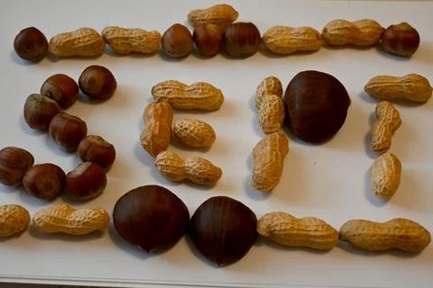 Peanuts in shells and hazelnuts on a white surface Stock Photos