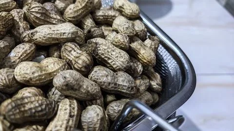 Peanuts in shells fill a metal mesh basket Stock Photos