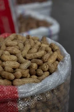Peanuts in shells filled inside large woven bag at street market Stock Photos