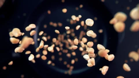 Peanuts slowly fall onto a hot frying pan in super slow motion. Video stock 280684800