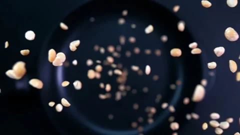 Peanuts slowly falling onto a hot frying pan on a dark background Stock Footage 282521531