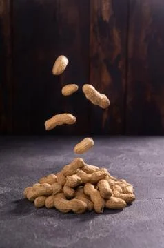 Peanuts soaring in the air on rustic textured background. Healthy food and diet. Stock Photos