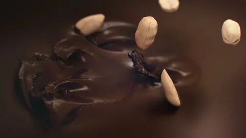 Peanuts Splashing Into Liquid Dark Chocolate in 4K Super slow motion Stock Footage 143465407