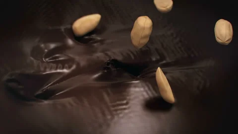 Peanuts Splashing Into Liquid Dark Chocolate in 4K Super slow motion Vídeos de archivo 143472965