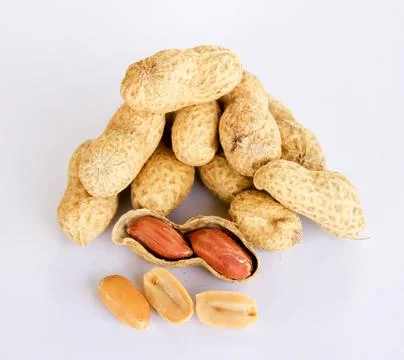 Peanuts stacked separately on a white background . Two kernels have already b Stock Photos
