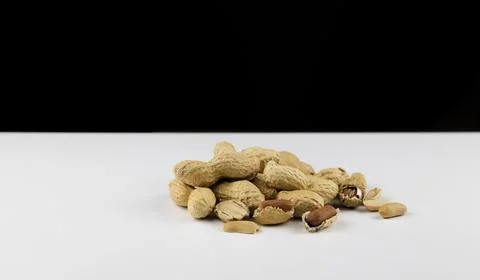 Peanuts in their shells on a white table, peeled and unshelled peanuts. Stock Photos