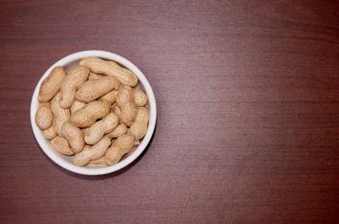 Peanuts uncleaned against a background of brown wood. Stock Photos