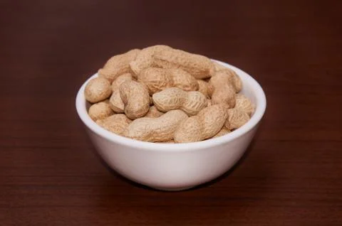 Peanuts uncleaned against a background of brown wood. Stock Photos