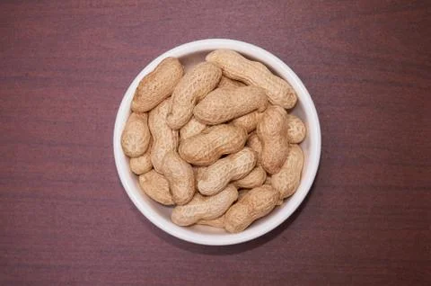 Peanuts uncleaned against a background of brown wood. Stock Photos
