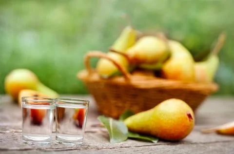 Pear brandy in shot glass.Pears in background. Stock Photos