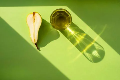 Pear split in half and a glass of pear lemonade on a green surface under the  Stock Photos