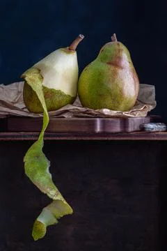 Pear still life on a paper bag, one pear cut open with the peel hanging Stock Photos