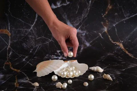 Pearls on the table in a shell and one in your hand Stock-Fotos