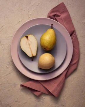 Pears of different types on a plain ceramic plate on a pink background Stock Photos