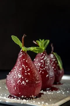 Pears in wine. Row of raditional dessert pears stewed in red wine on black ba Stock Photos