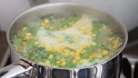Peas, corn and green beans boiling in water in iron pot Stock Footage 105786600