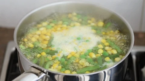 Peas, corn and green beans boiling in water in iron pot Stock-Footage 105786683