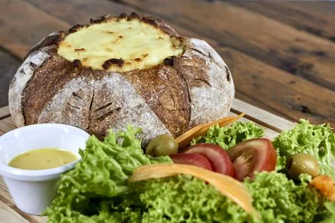 Peasant bread stuffed with meat and chicken covered with cheese with salad Stock Photos