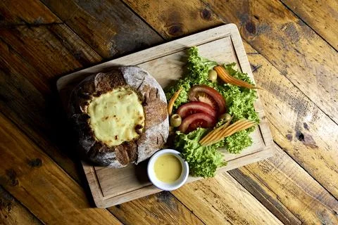 Peasant bread stuffed with meat and chicken covered with cheese with salad Stock Photos