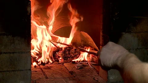 The peasant crushes burning firewood in a Russian oven for baking bread Stock Footage 85778971