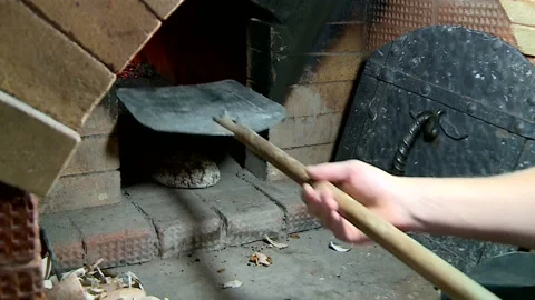 Peasant puts rye bread in a hot Russian oven on a wooden shovel Stockbeeldmateriaal 85778687