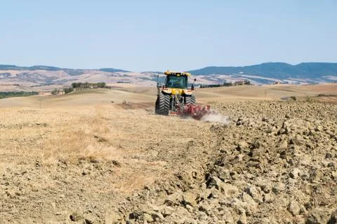 Peasant on the tractor while preparing the field for sowing Stock Photos