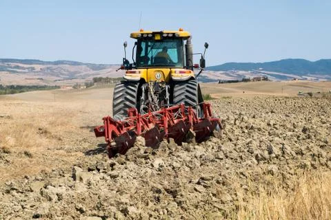 Peasant on the tractor while preparing the field for sowing Stock Photos