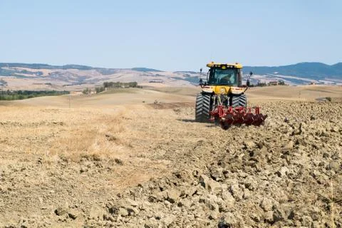Peasant on the tractor while preparing the field for sowing Stock Photos
