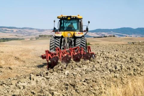 Peasant on the tractor while preparing the field for sowing Stock Photos