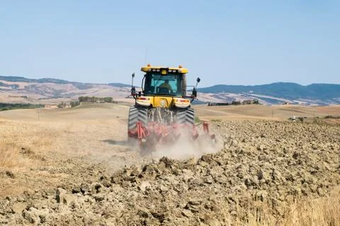 Peasant on the tractor while preparing the field for sowing Stock Photos