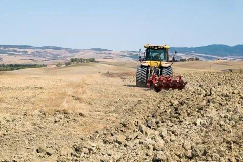 Peasant on the tractor while preparing the field for sowing Stock Photos