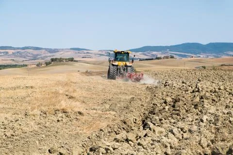 Peasant on the tractor while preparing the field for sowing Stock Photos