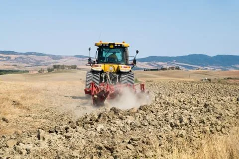 Peasant on the tractor while preparing the field for sowing Stock Photos