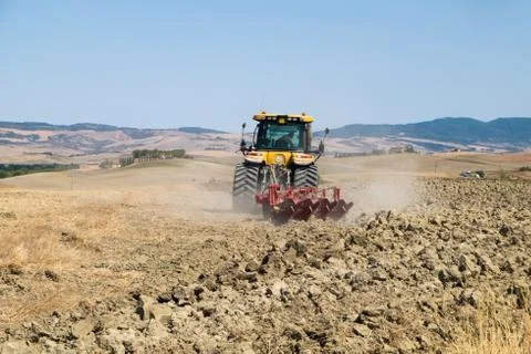 Peasant on the tractor while preparing the field for sowing Stock Photos