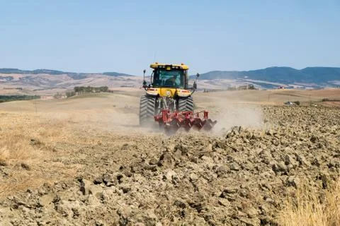 Peasant on the tractor while preparing the field for sowing Stock Photos