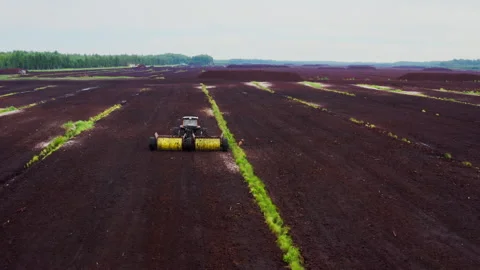 Peat extraction harvesting fields aerial view. Tractor with rollers loosens peat Stock-Footage 299800701