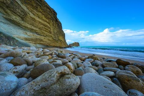 Pebble and sandy beach, high mountain by the ocean, beautiful ocean views Stock Photos