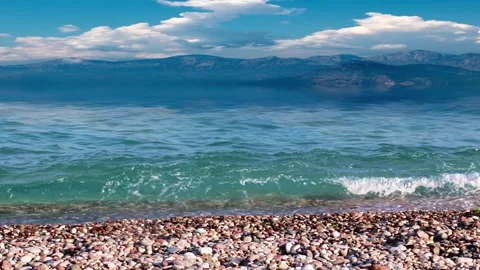 Pebble beach and mountain peaks Video stock 337705137
