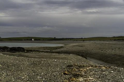 Pebble beach and pond, cloudy sky. Stock Photos