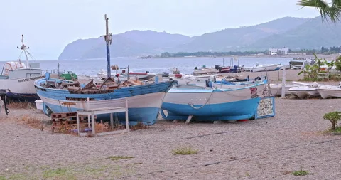 Pebble beach and row of palm trees of Patti marittima. Patti is a town and co Vidéo 276103883