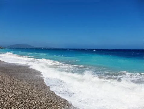 A pebble beach on the background of a two-tone sea defocus Stock Photos