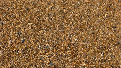 Pebble beach with a breaking wave in the distance Stock Photos