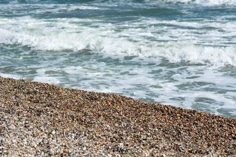 A pebble beach with gentle waves lapping the shore, creating a tranquil coa.. Stock Photos