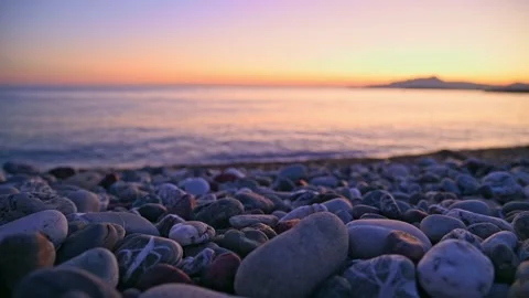 Pebble beach with gentle waves rolling toward shore at sunset Stock Footage 345080547
