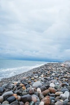 Pebble beach with gentle waves under a cloudy sky Stock Photos