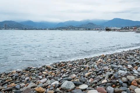 Pebble beach with gentle waves under a cloudy sky Stock Photos